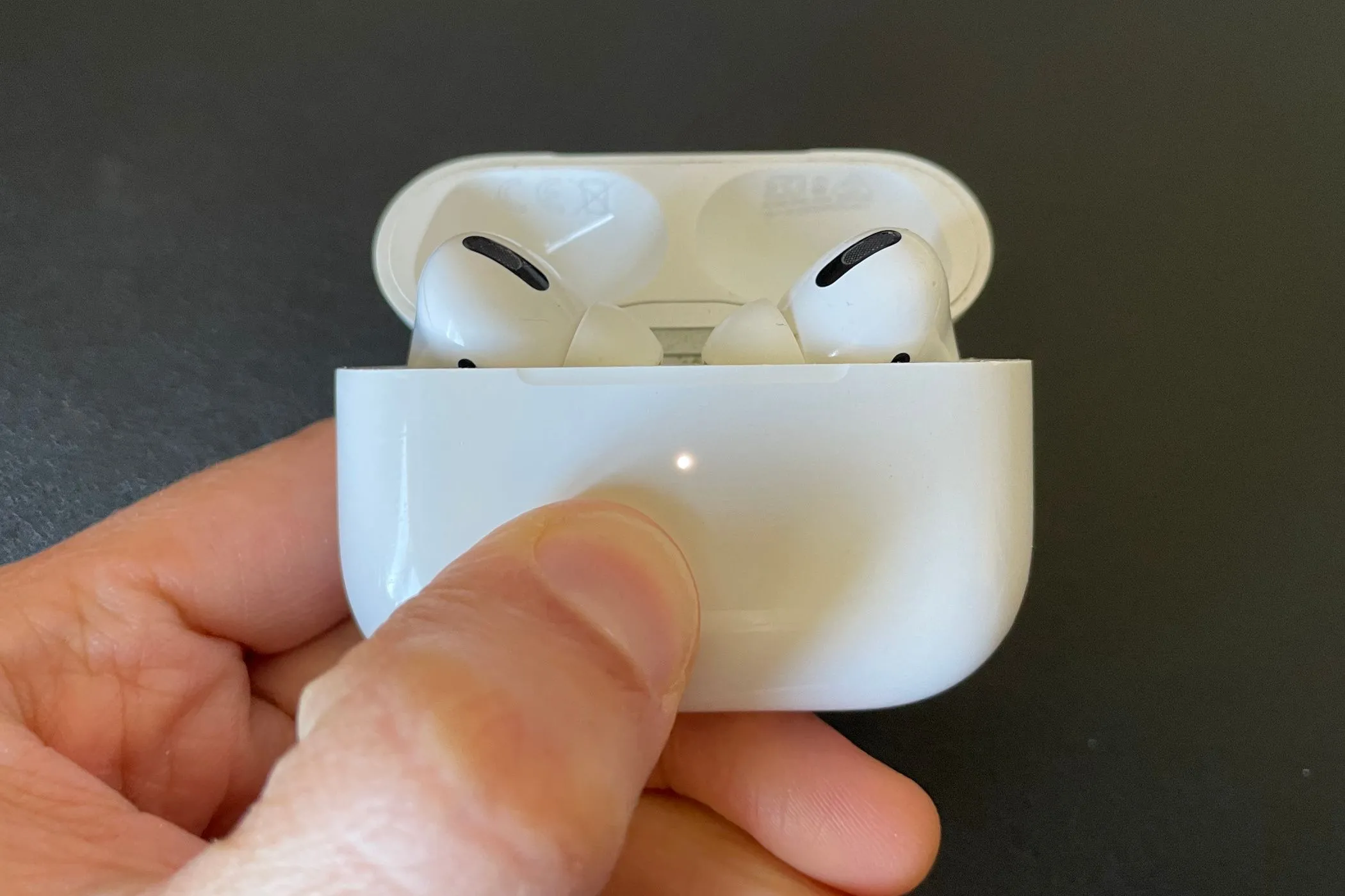 AirPods Pro nằm gọn trong hộp sạc màu trắng, đèn báo trạng thái màu trắng bật sáng, thể hiện sự tiện lợi nhưng cũng phản ánh vấn đề pin không thể thay thế.