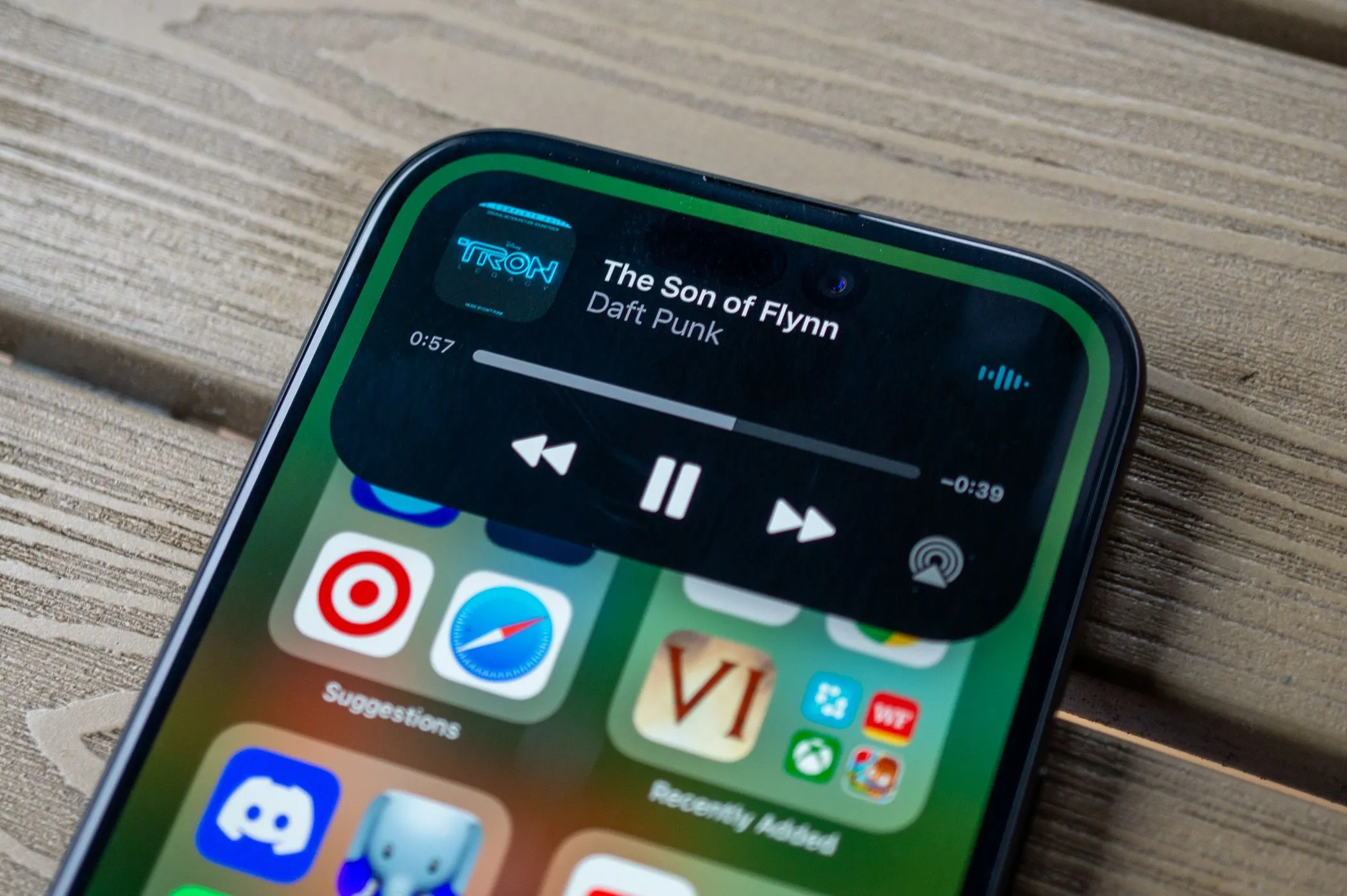 Ảnh iPhone 15 màu hồng hiển thị tính năng Dynamic Island với giao diện điều khiển nhạc trên màn hình khóa.
