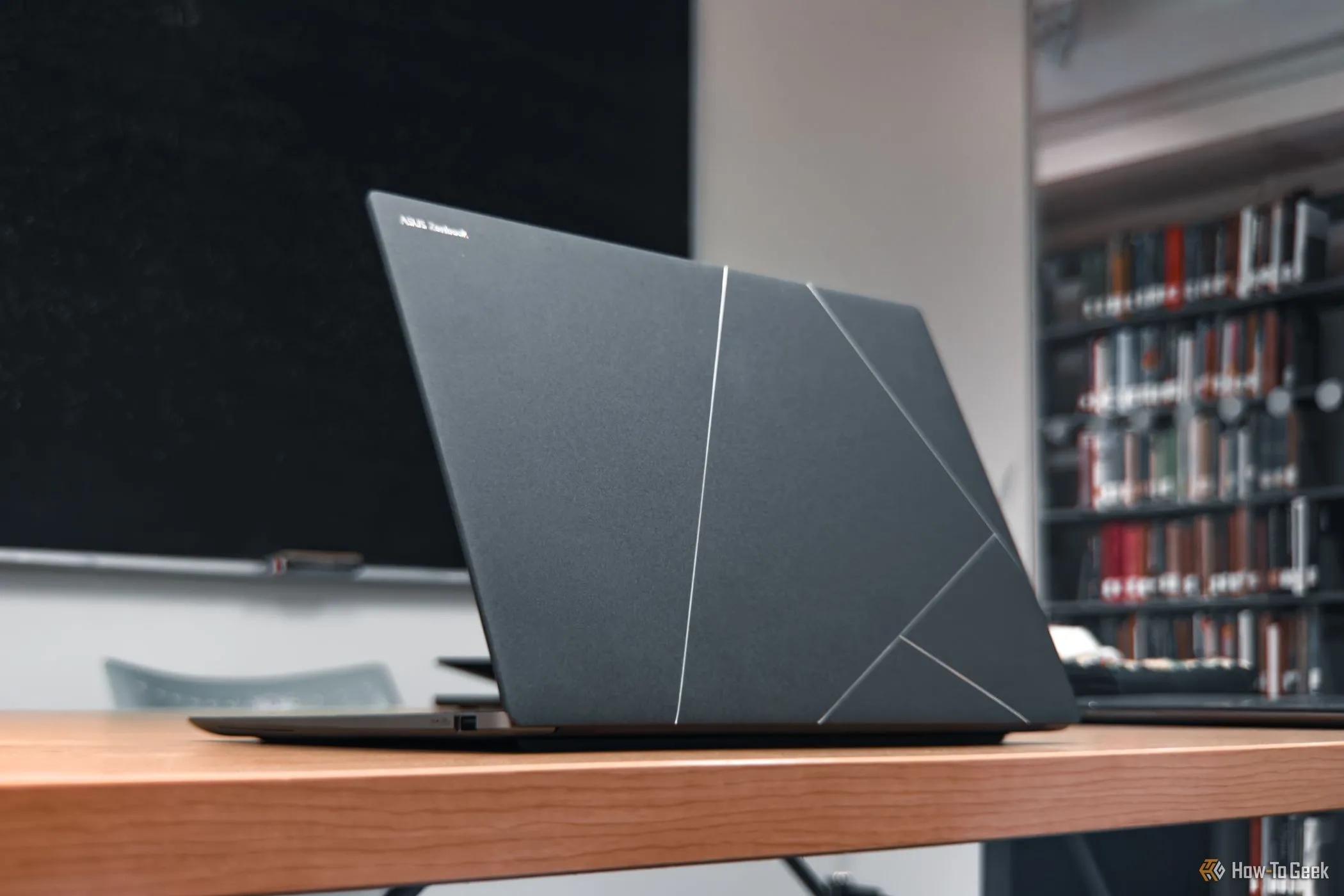 ASUS Zenbook S 14 mở màn hình trên bàn gỗ, tôn vinh thiết kế hiện đại và bàn phím tiện lợi của dòng laptop cao cấp này.