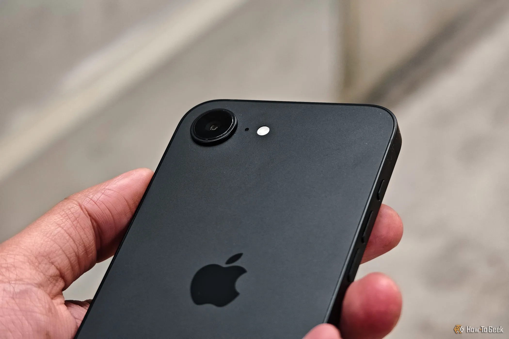 Cận cảnh camera đơn 48MP của iPhone 16e màu trắng khi cầm trên tay, minh họa bước nâng cấp đáng kể cho người dùng iPhone cũ.