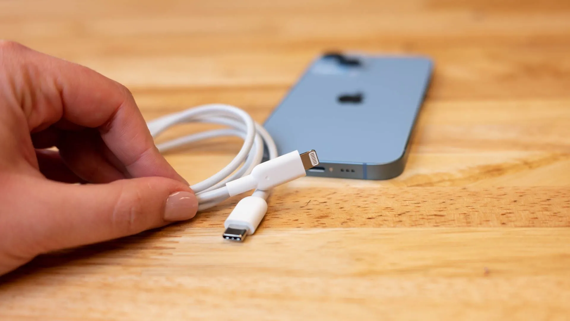 Cáp chuyển đổi USB-C sang Lightning và iPhone, tượng trưng cho quá trình thay đổi chuẩn sạc từ Lightning sang USB-C theo quy định EU
