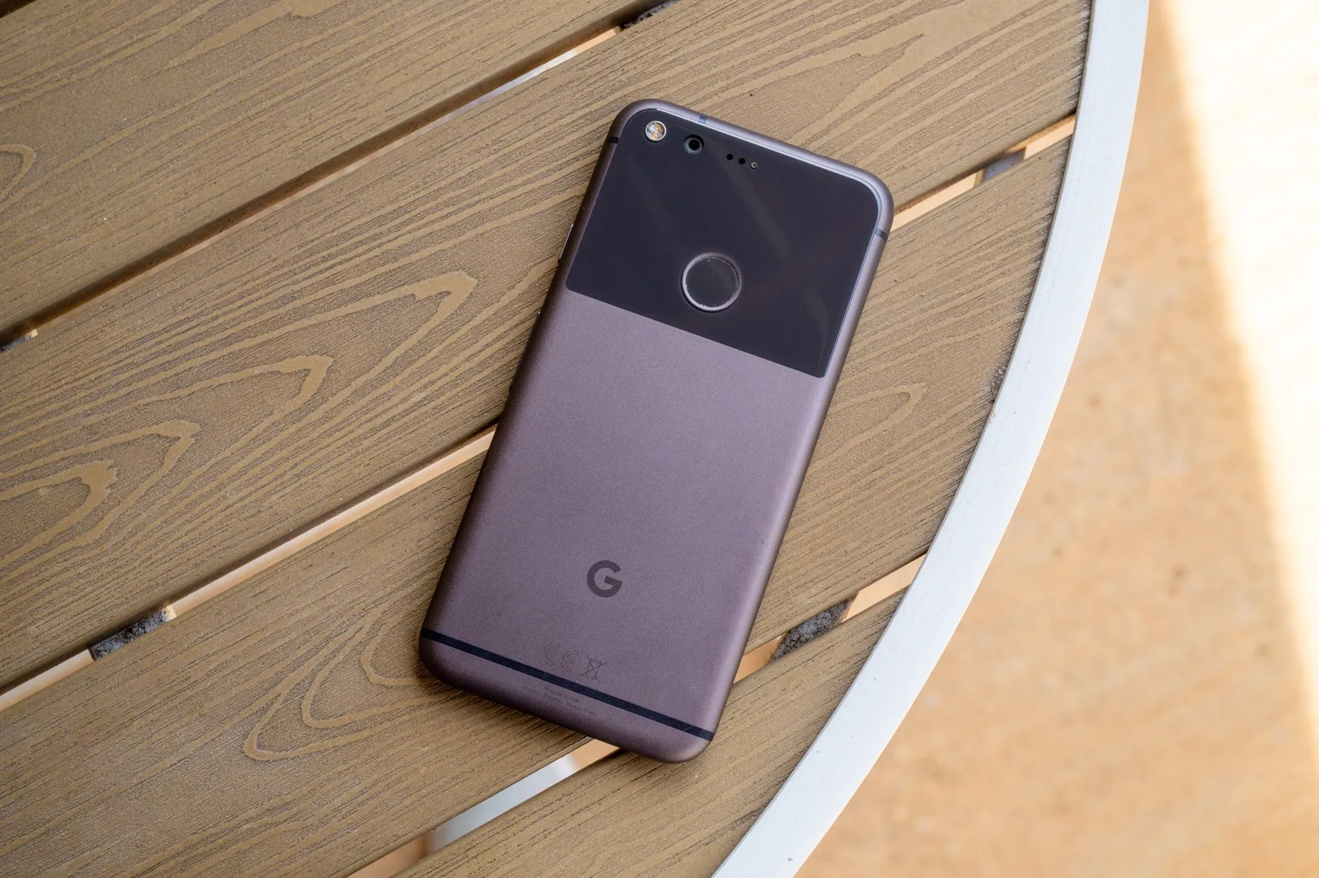 Điện thoại Google Pixel thế hệ đầu tiên màu đen bạc đặt trên bàn, với thiết kế mặt lưng độc đáo kết hợp kim loại và kính, tượng trưng cho sự khởi đầu của dòng Pixel tập trung vào camera.