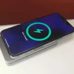 Điện thoại iPhone đang được sạc không dây với bộ sạc MagFlow Qi2 đặt nằm phẳng, minh họa công nghệ sạc không dây hiện tại.