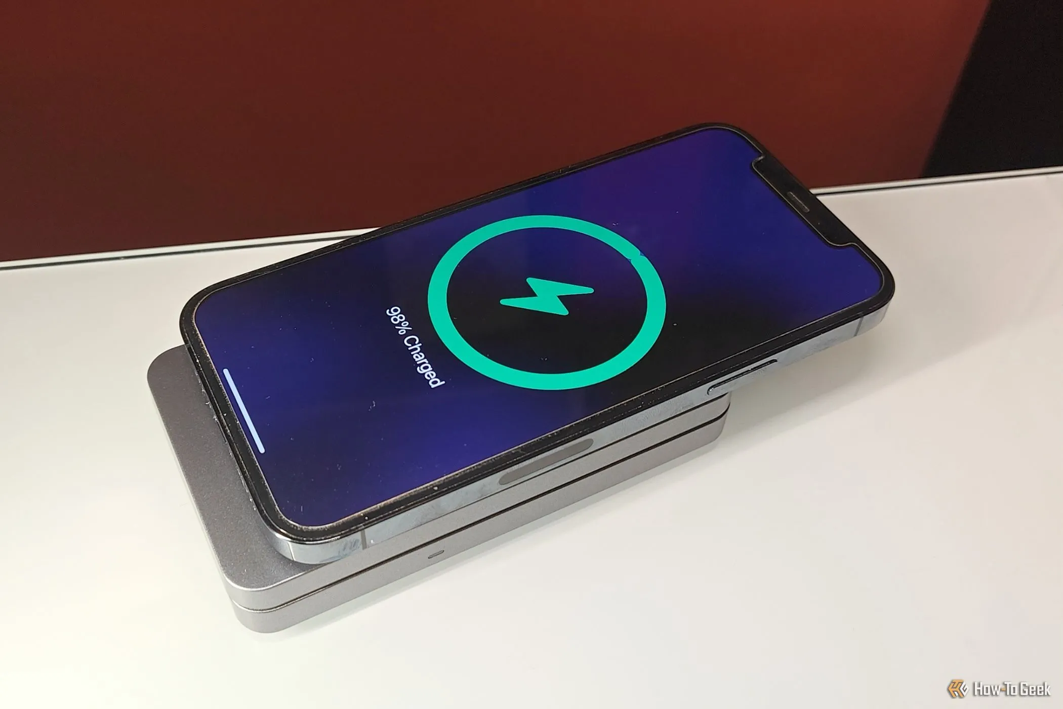 Điện thoại iPhone đang được sạc không dây với bộ sạc MagFlow Qi2 đặt nằm phẳng, minh họa công nghệ sạc không dây hiện tại.