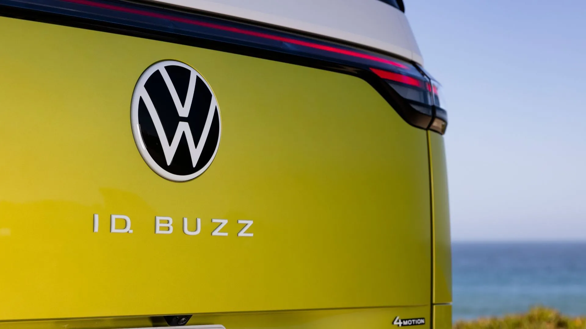 Huy hiệu &quot;ID. Buzz&quot; và logo Volkswagen trên cửa sau xe điện 2025 màu vàng chanh, đại diện cho kỷ nguyên di động điện tử của hãng.