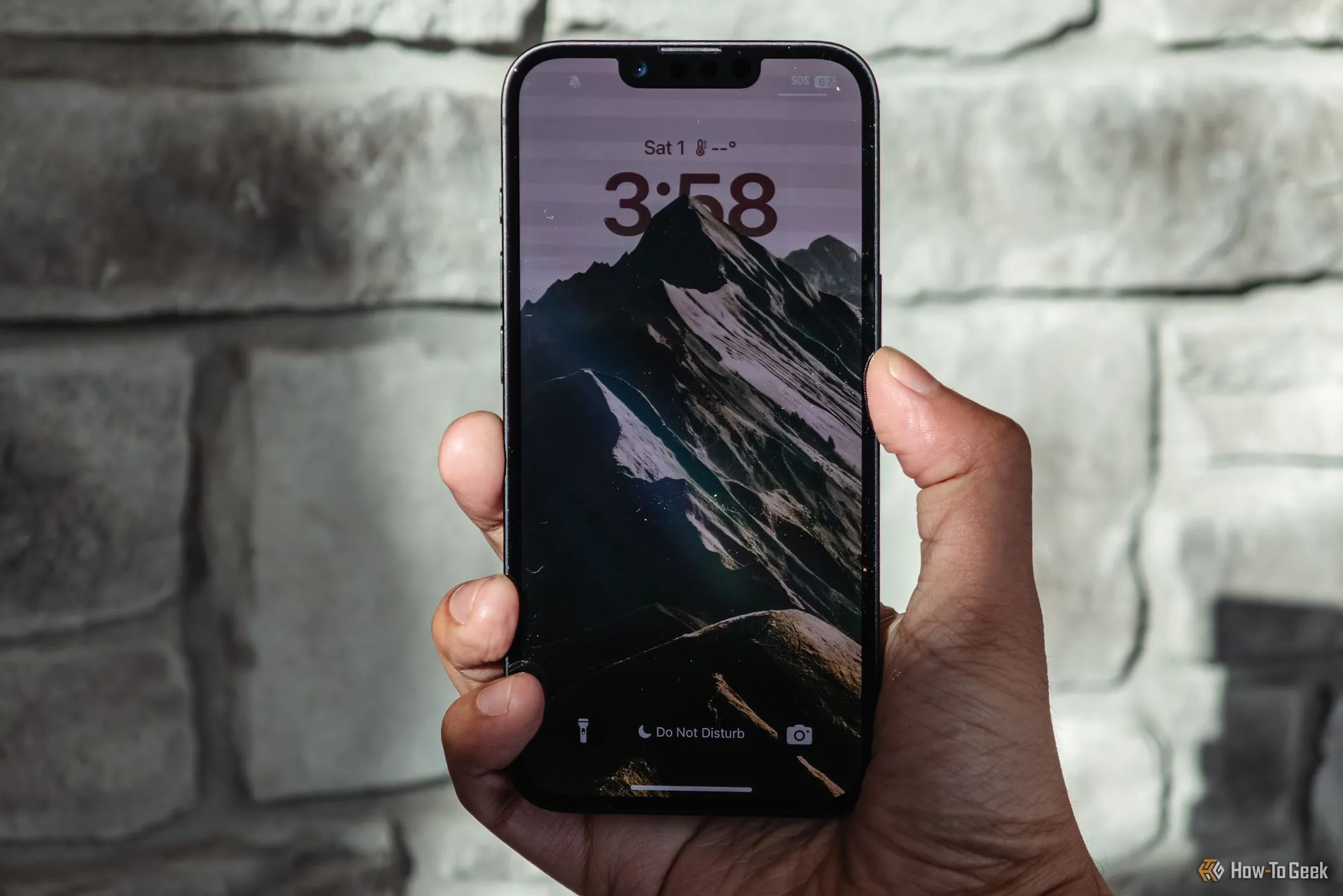 iPhone 16e màu trắng được cầm trên tay hiển thị màn hình khóa, cho thấy tần số quét 60Hz cơ bản của thiết bị.