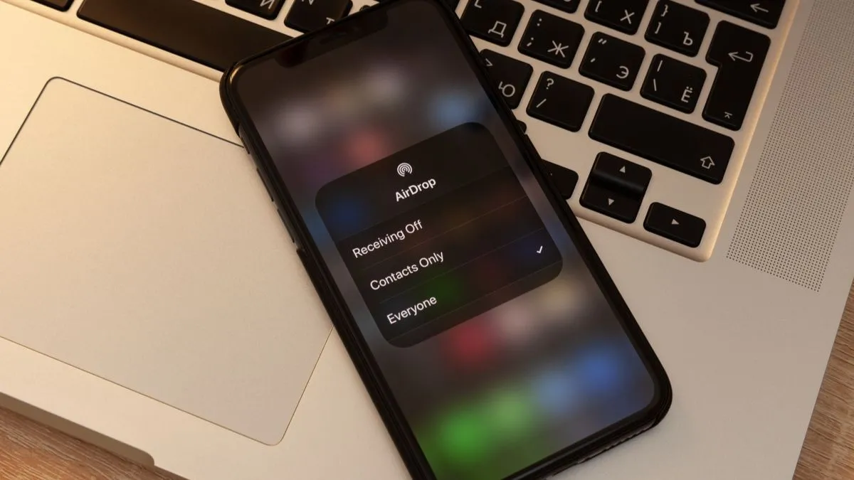 iPhone hiển thị thông báo AirDrop đặt trên MacBook, tượng trưng cho sự liền mạch của hệ sinh thái Apple.