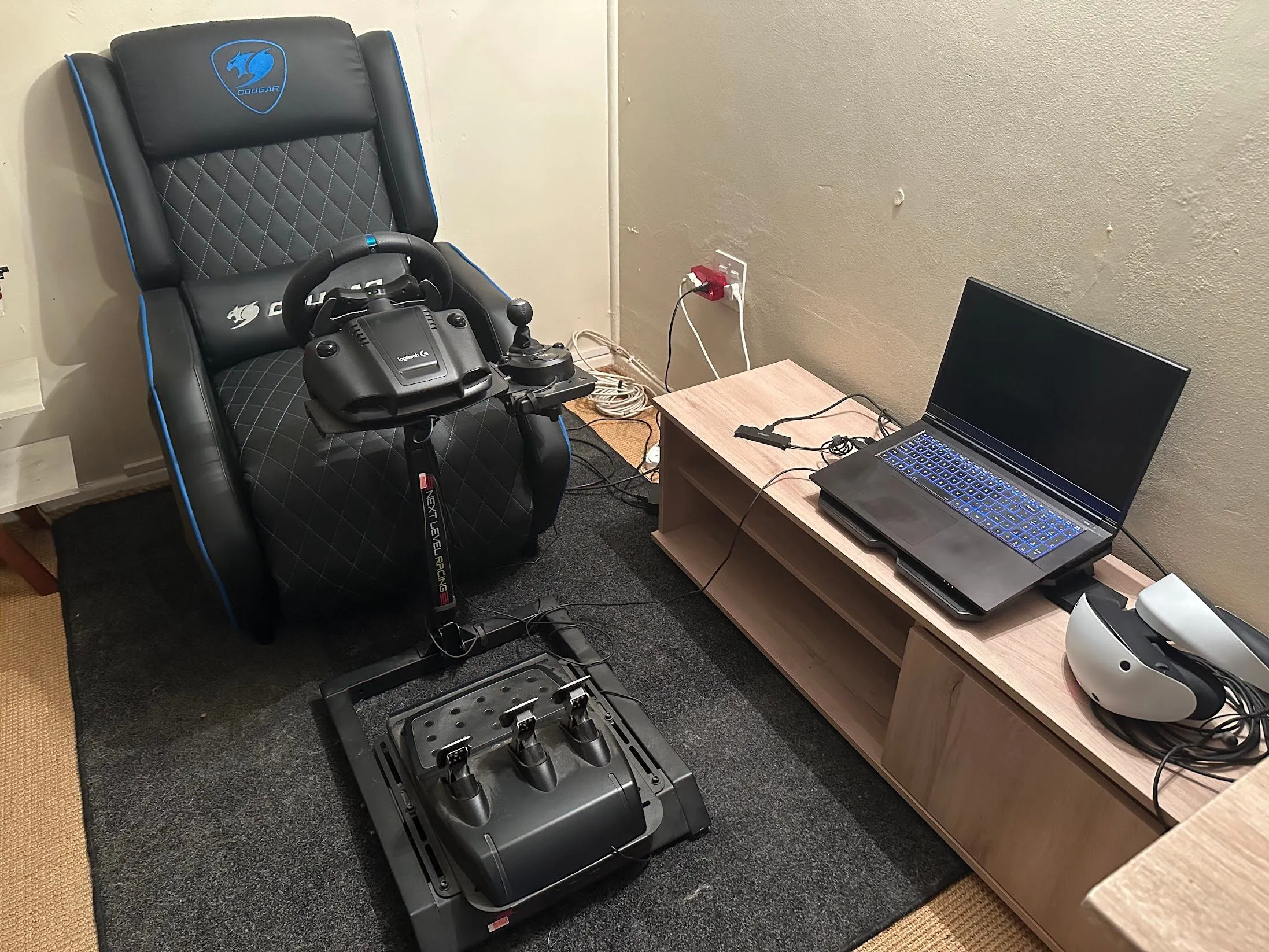 Laptop chơi game được đặt xa khu vực làm việc chính, gần kính VR và bộ mô phỏng đua xe, nhằm giảm tiếng ồn trực tiếp đến người dùng.