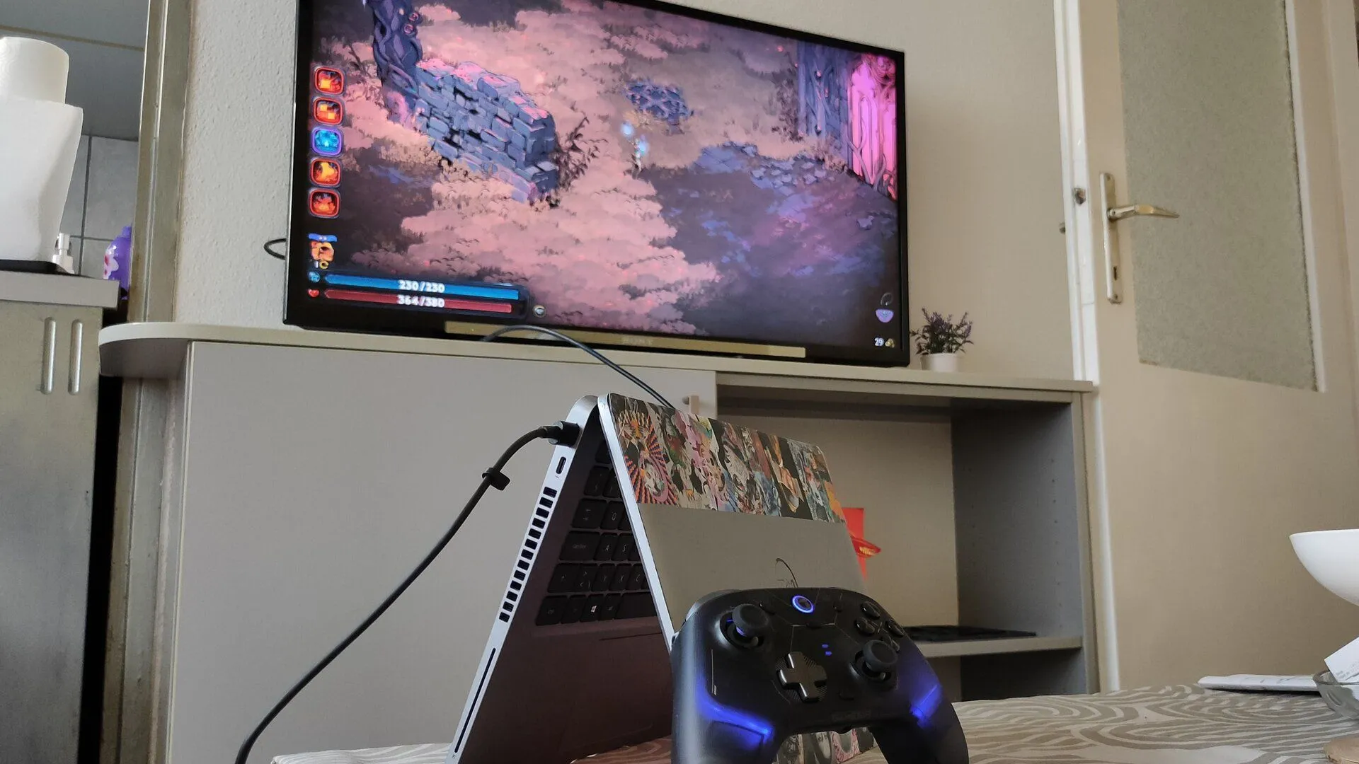 Laptop Dell kết nối với TV và tay cầm chơi game, minh họa cách tận dụng phần cứng cũ để thưởng thức các tựa game kinh điển với trải nghiệm thoải mái, phù hợp cho người chơi muốn tiết kiệm.