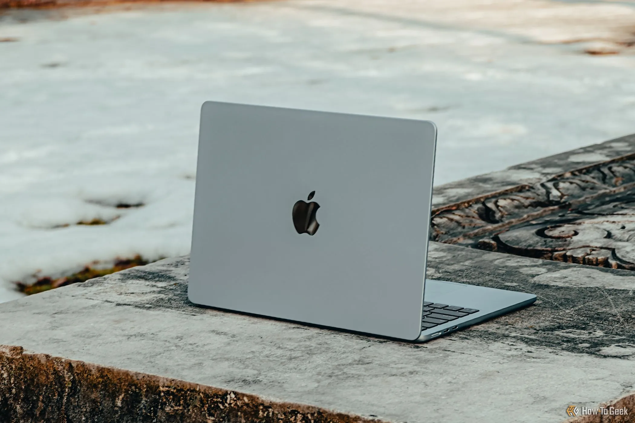 Mẫu MacBook Air M4 màu xanh nhạt đặt trên ghế đá, thể hiện thiết kế mỏng nhẹ nhưng vẫn khó sửa chữa