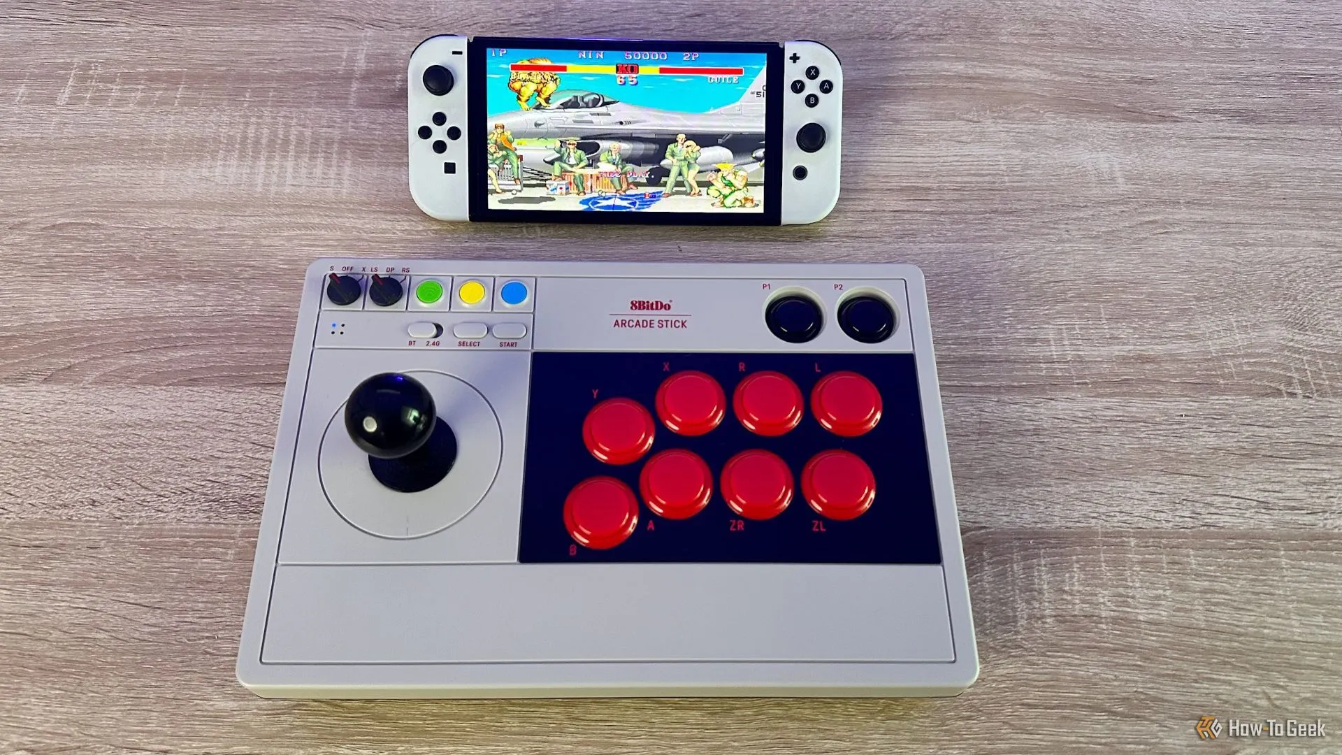 Máy chơi game Nintendo Switch OLED kết nối với 8BitDo Arcade Stick đang hiển thị trò chơi Street Fighter 2 cổ điển.