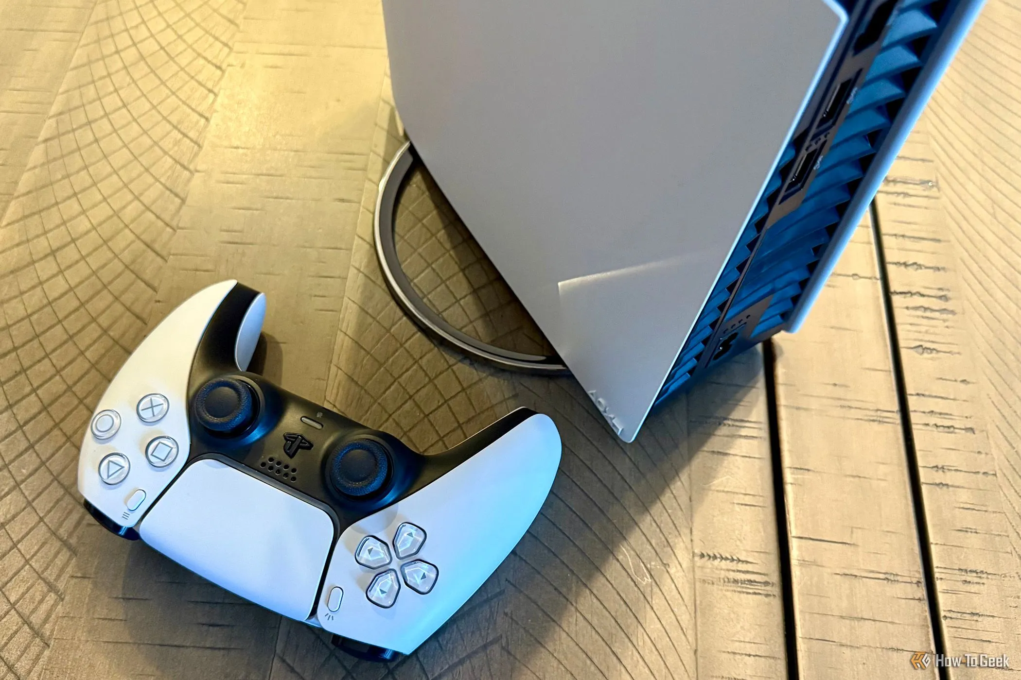 Máy chơi game PlayStation 5 Pro với chân đế dọc và tay cầm DualSense không dây, minh họa hệ sinh thái console và hạn chế tương thích tay cầm bên thứ ba.