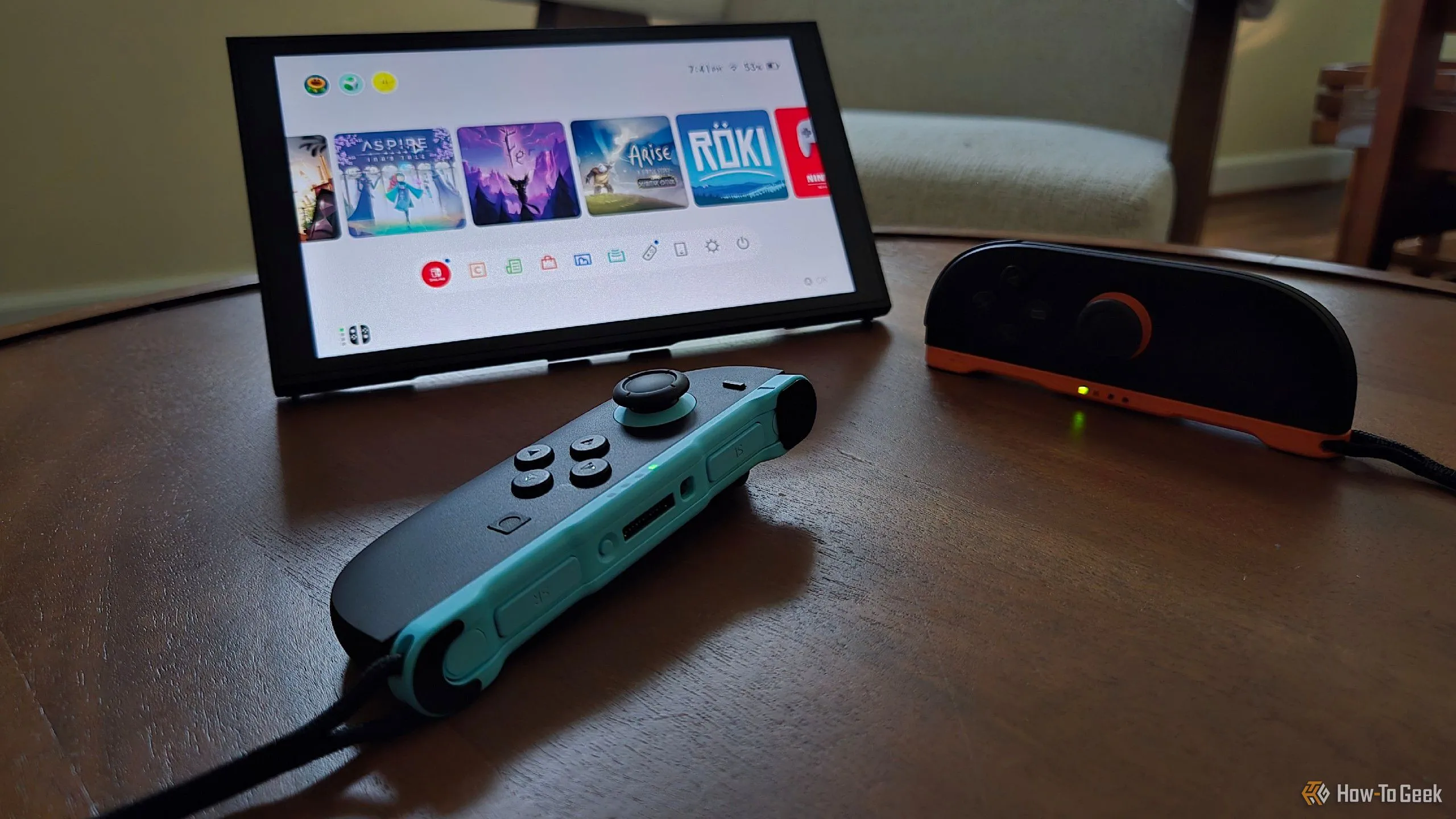 Máy Nintendo Switch 2 đứng vững bằng chân đế tích hợp, với hai tay cầm Joy-Con 2 ở phía trước, một tay cầm được dùng làm chuột.