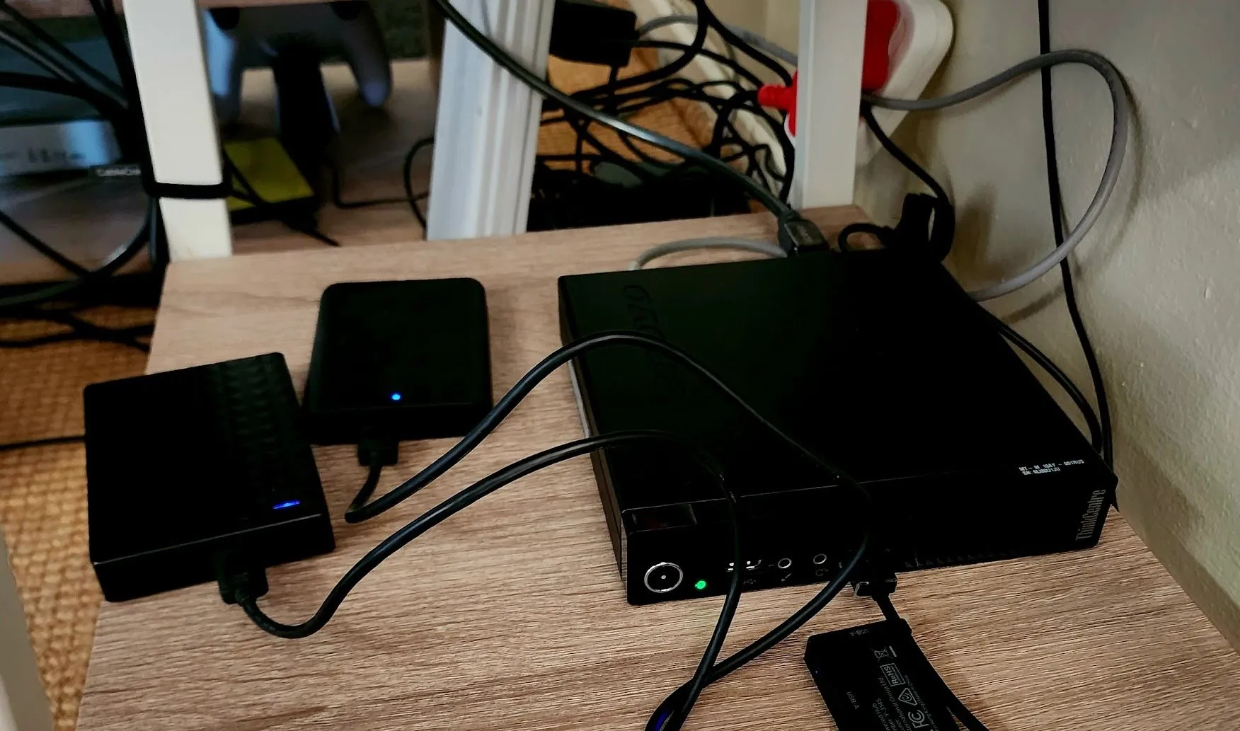 Máy tính mini đóng vai trò máy chủ Plex cùng nhiều ổ cứng USB gắn ngoài, đặt gọn gàng trên kệ bàn.