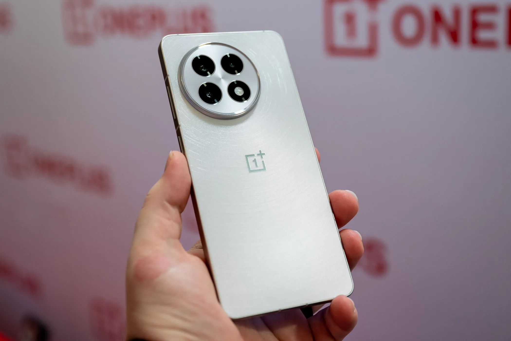Một người đang cầm điện thoại OnePlus 13R màu trắng bạc, thể hiện kích thước tổng thể và kiểu dáng hiện đại.