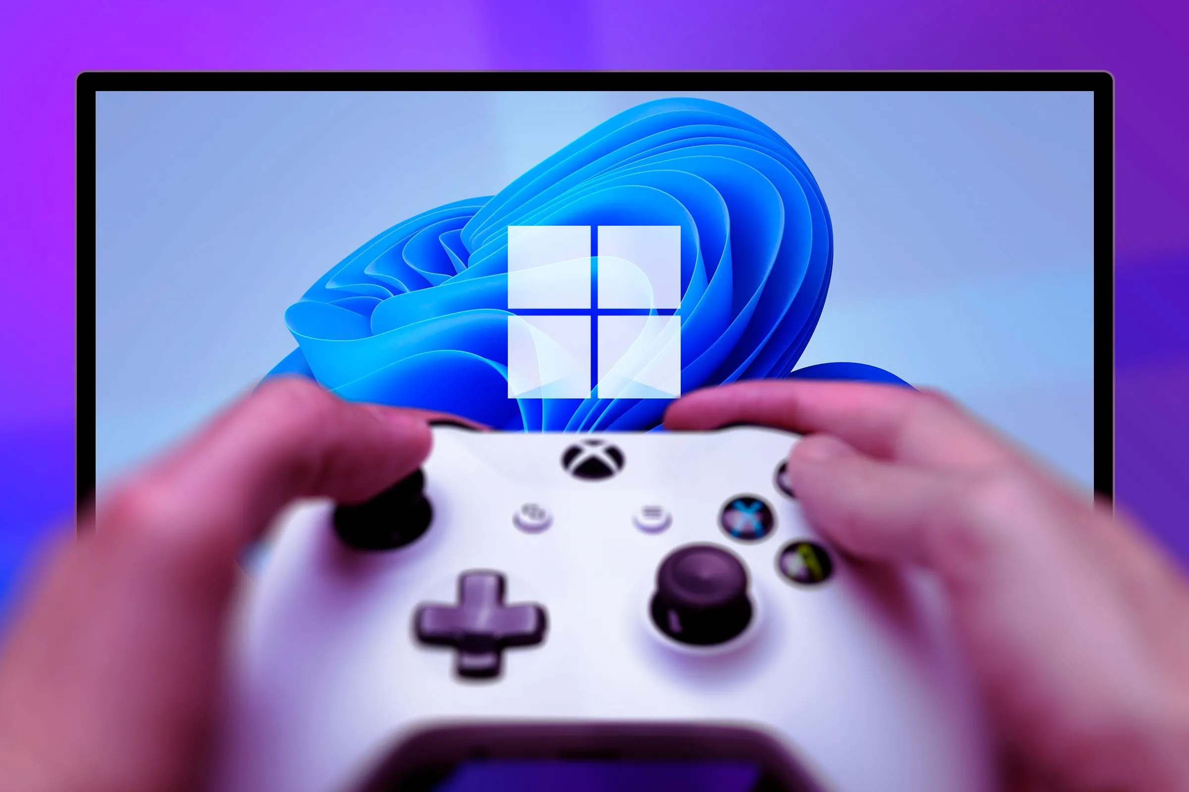 Một người đang cầm tay cầm Xbox One màu đen, phía sau là màn hình máy tính với hình nền Windows 11.