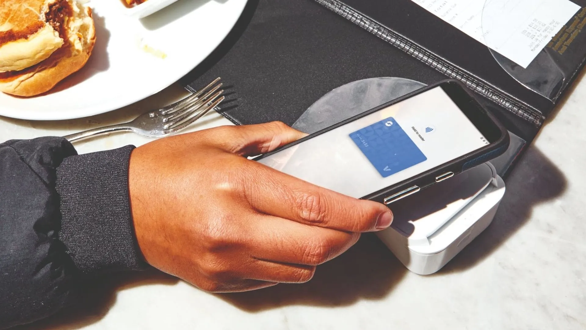 Một người dùng đang thực hiện giao dịch thanh toán không chạm bằng điện thoại thông minh qua Google Wallet tại một máy POS tích hợp NFC.