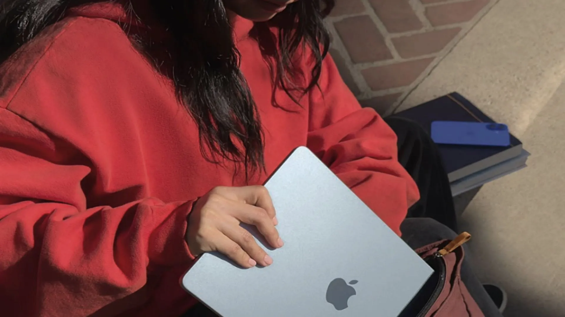 Một sinh viên đang cho MacBook Air 13 inch M4 màu xanh đậm vào ba lô, tượng trưng cho sự tiện lợi và gọn nhẹ lý tưởng cho học tập.