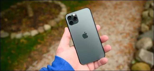 Người dùng cầm iPhone 11 Pro trong tay, minh họa việc sử dụng điện thoại khi sạc không dây hoặc kiểm tra tốc độ sạc hiệu quả.