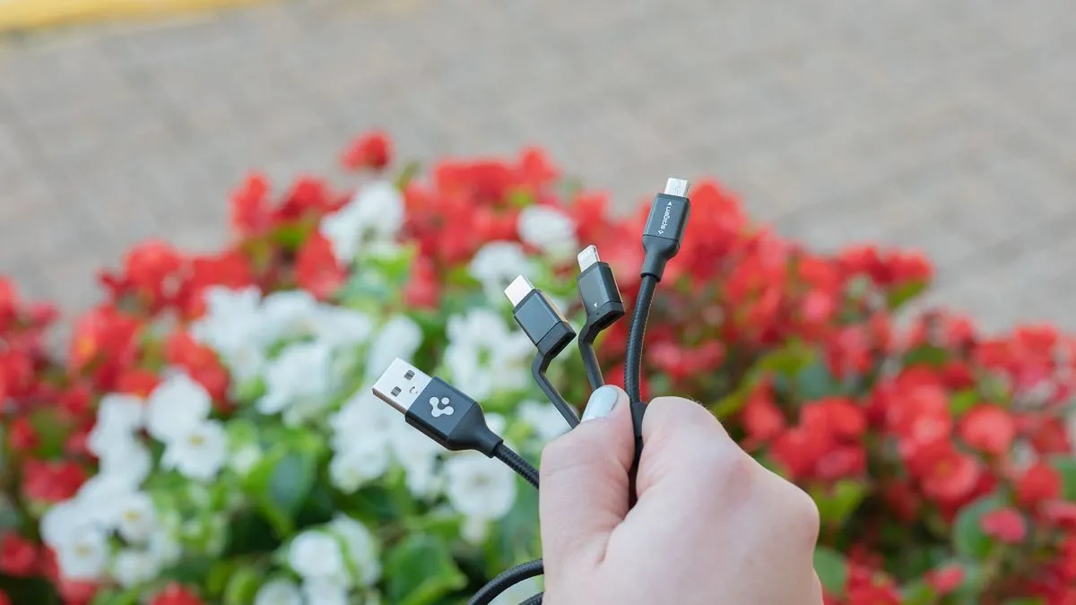 Người dùng đang cầm cáp sạc đa năng Spigen DuraSync 3 trong 1, thể hiện sự tiện lợi của nhiều loại đầu sạc.