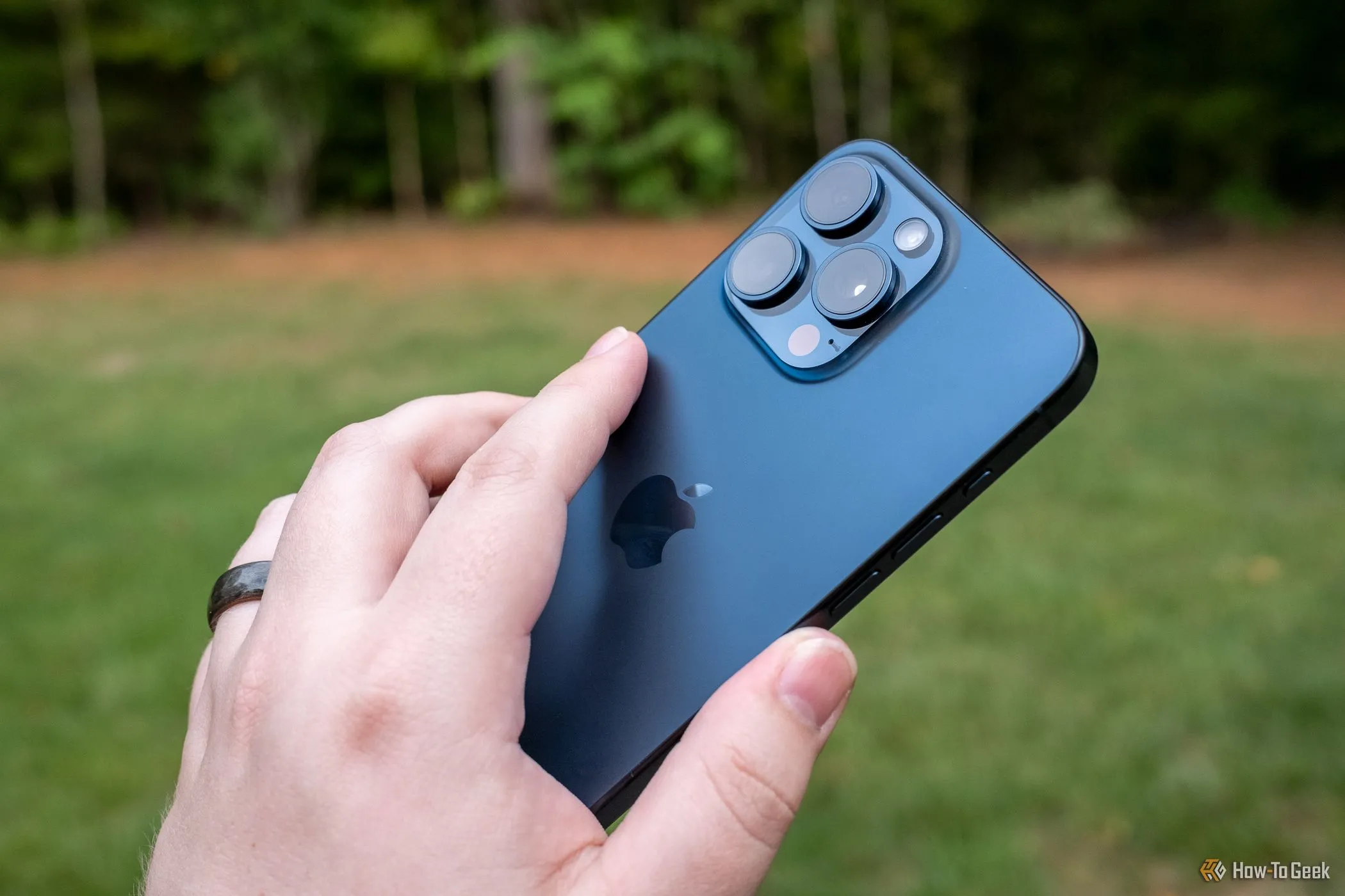 Người dùng đang cầm mặt lưng iPhone 15 Pro Max, minh họa việc sử dụng cử chỉ Chạm hai lần để kích hoạt Phím tắt