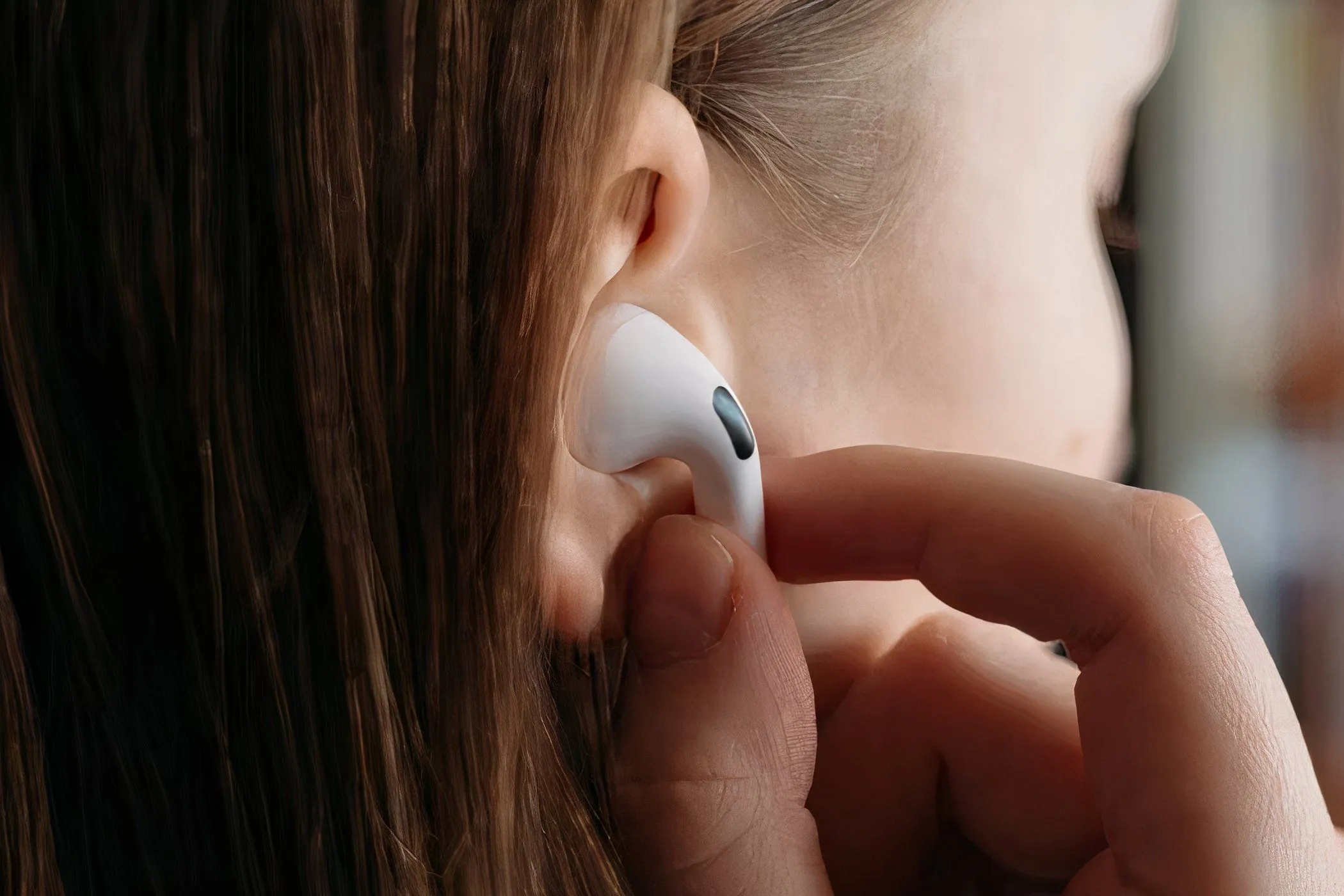 Người phụ nữ đang đeo tai nghe AirPods Pro vào tai, thể hiện sự tiện lợi và trải nghiệm âm thanh không dây liền mạch trong hệ sinh thái Apple.