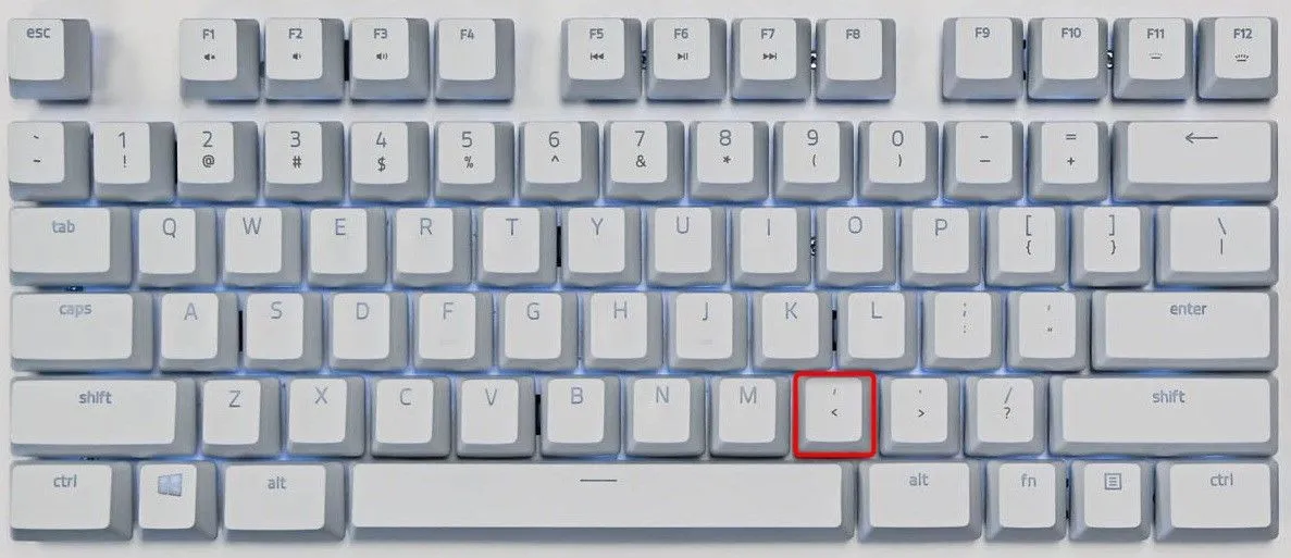 Phím dấu phẩy (,) được đánh dấu nổi bật trên bàn phím QWERTY, minh họa vị trí để tua ngược từng khung hình YouTube.