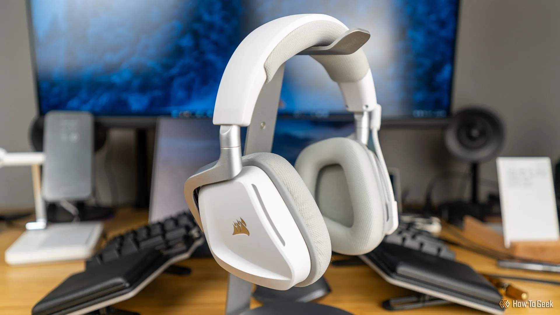 Tai nghe chơi game không dây Corsair Void Wireless V2 màu trắng đặt trên giá đỡ, hòa mình vào không gian setup gaming