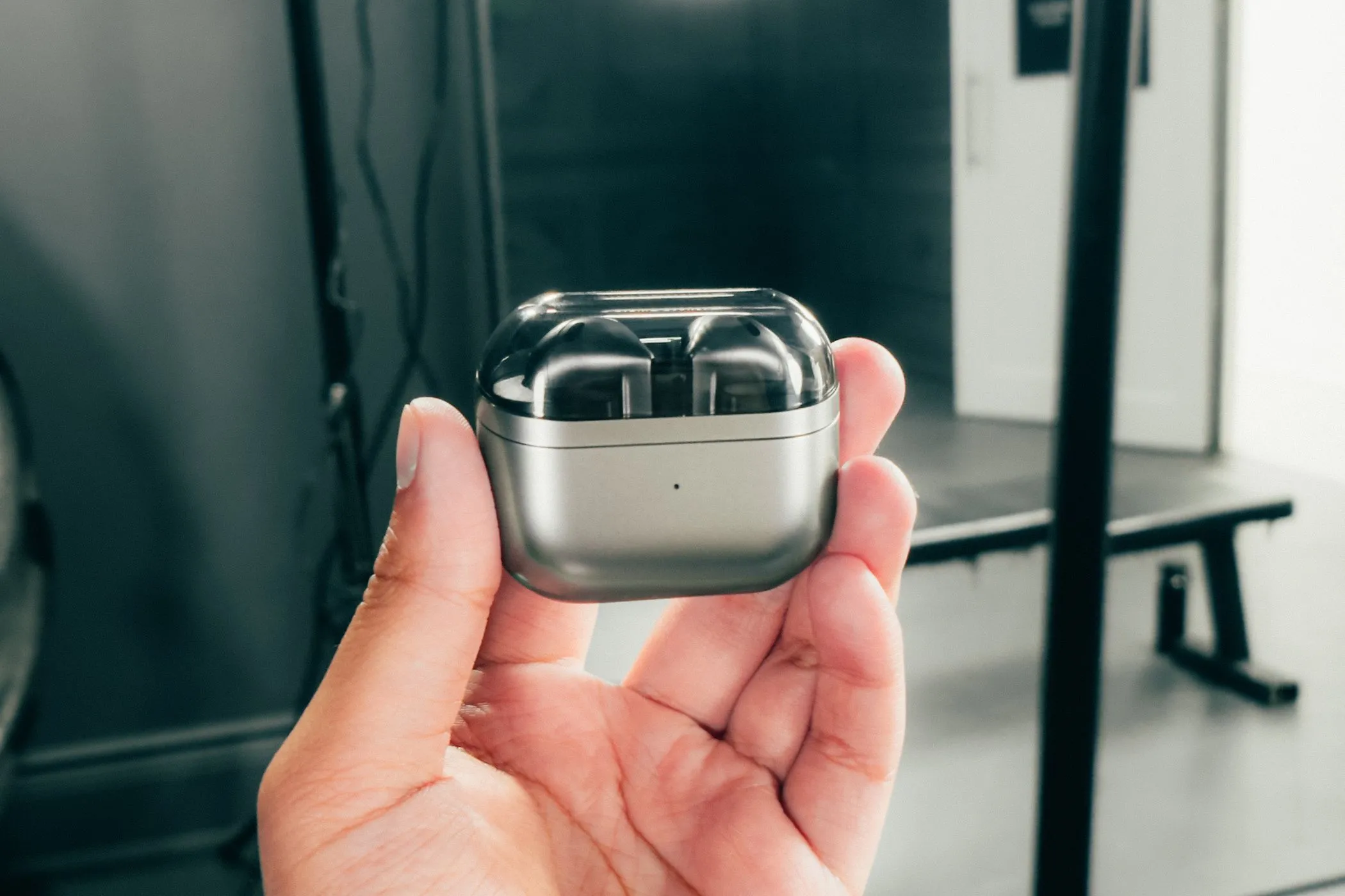 Tai nghe Samsung Galaxy Buds 3 màu trắng nằm gọn trong hộp sạc đóng kín, được cầm trên tay, sau khi nhận bản cập nhật cải thiện hiệu năng.