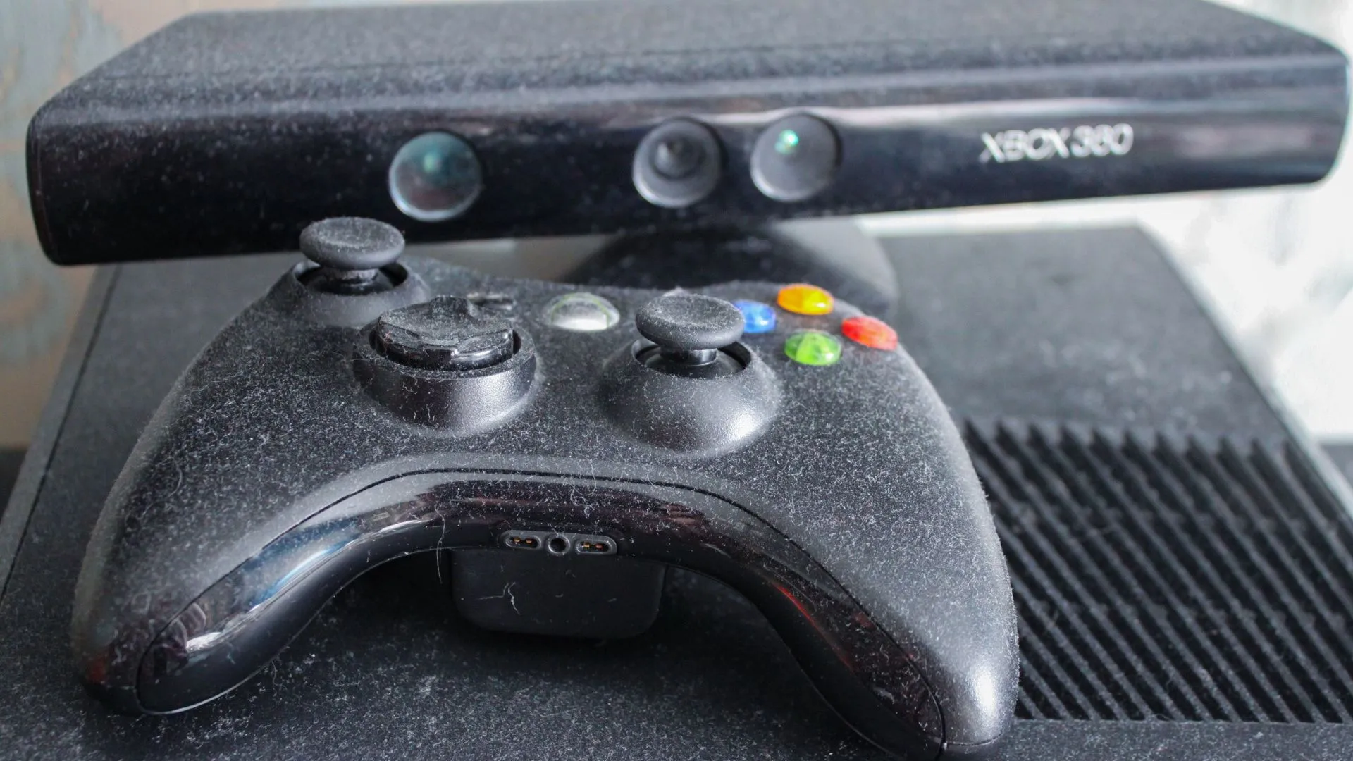 Tay cầm Xbox 360 cũ bám bụi và camera Kinect, gợi nhớ về tuổi thọ và sự hao mòn của các thiết bị chơi game.
