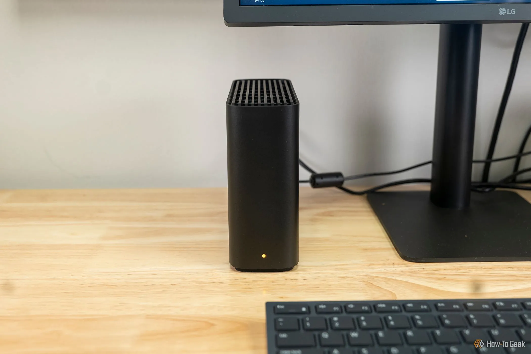 Thiết bị lưu trữ mạng Synology BeeStation đặt cạnh màn hình máy tính, tượng trưng cho giải pháp lưu trữ và chạy Jellyfin bằng Docker trên nền tảng NAS.