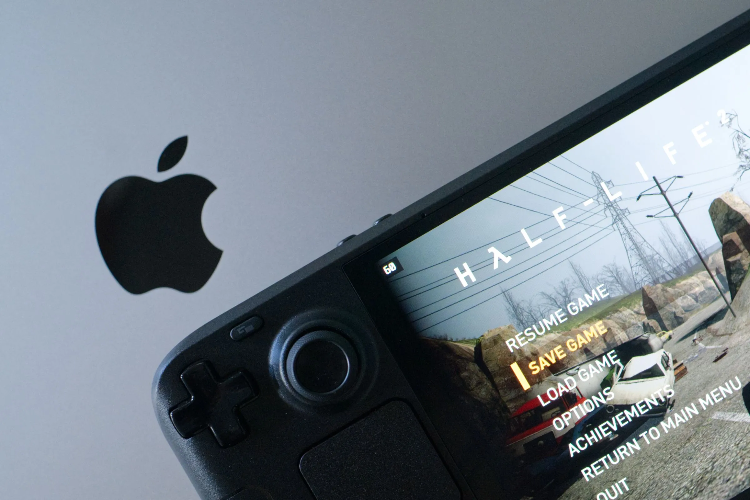 Trò chơi Half-Life 2 đang chạy trên Steam Deck OLED đặt cạnh MacBook Pro, tượng trưng cho giá trị và tính di động của các thiết bị chơi game cầm tay.