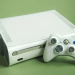 Xbox 360 màu trắng cùng tay cầm điều khiển, tượng trưng cho một kỷ nguyên chơi game đã qua nhưng vẫn được săn đón thông qua giả lập và công nghệ mới.