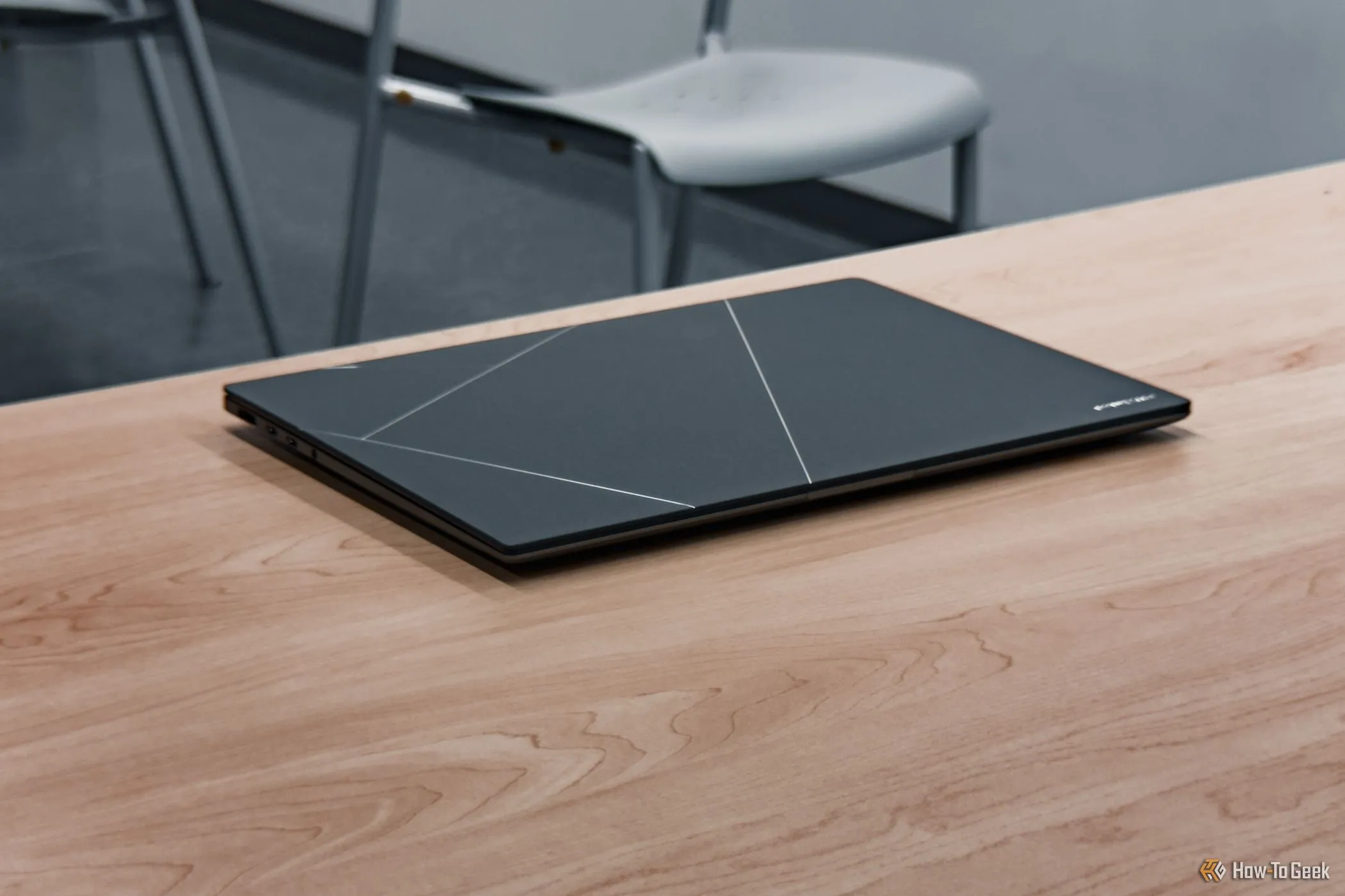 Zenbook S 14 2024 gập lại trên bàn gỗ, thể hiện sự gọn nhẹ và chất liệu Ceraluminum bền bỉ, dễ dàng mang đi làm hoặc học.